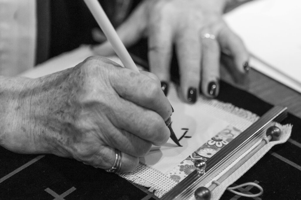 Close-up of an elderly hand practicing calligraphy, highlighting cultural traditions and artistry.